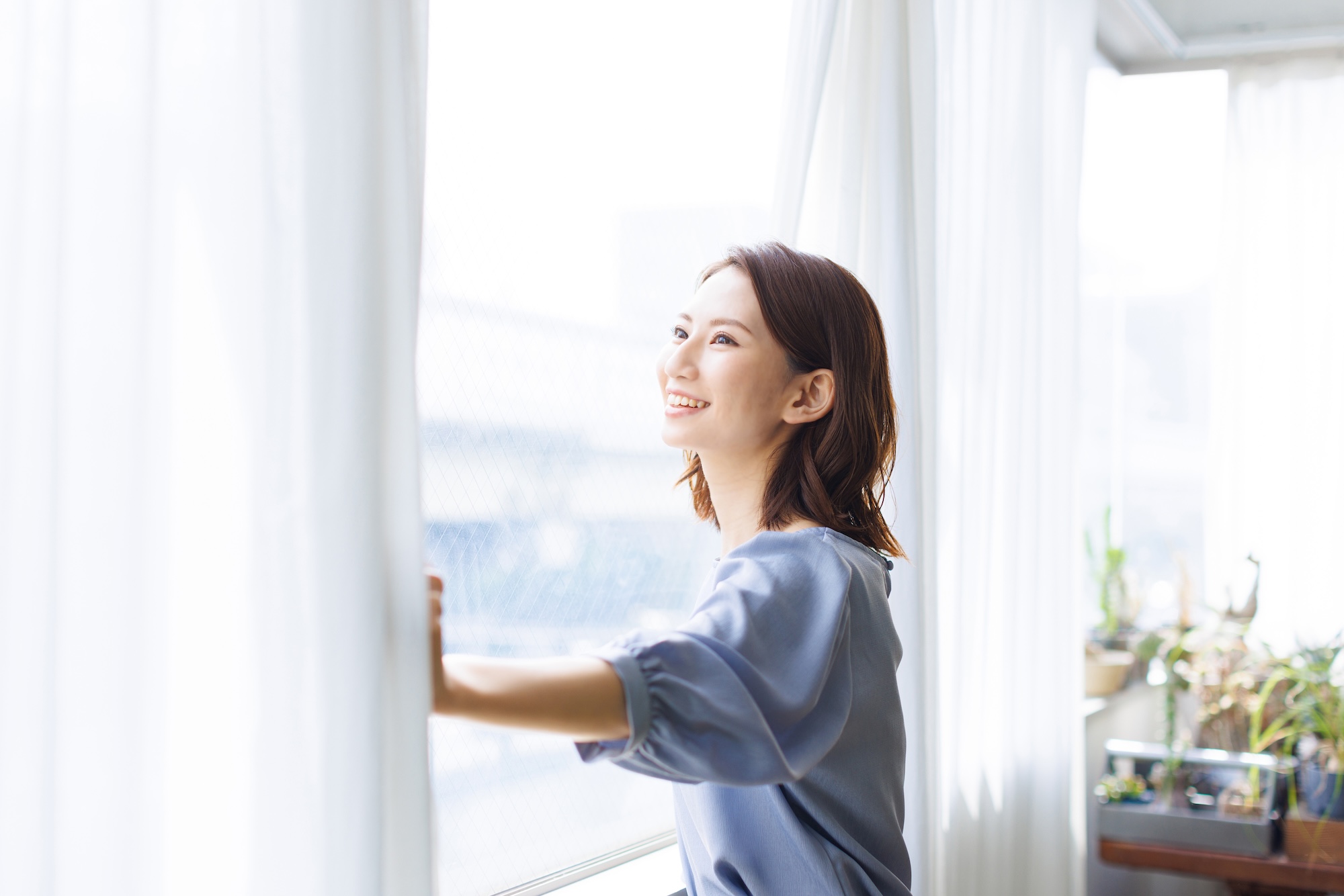 快適な室内から外を眺める窓辺の女性